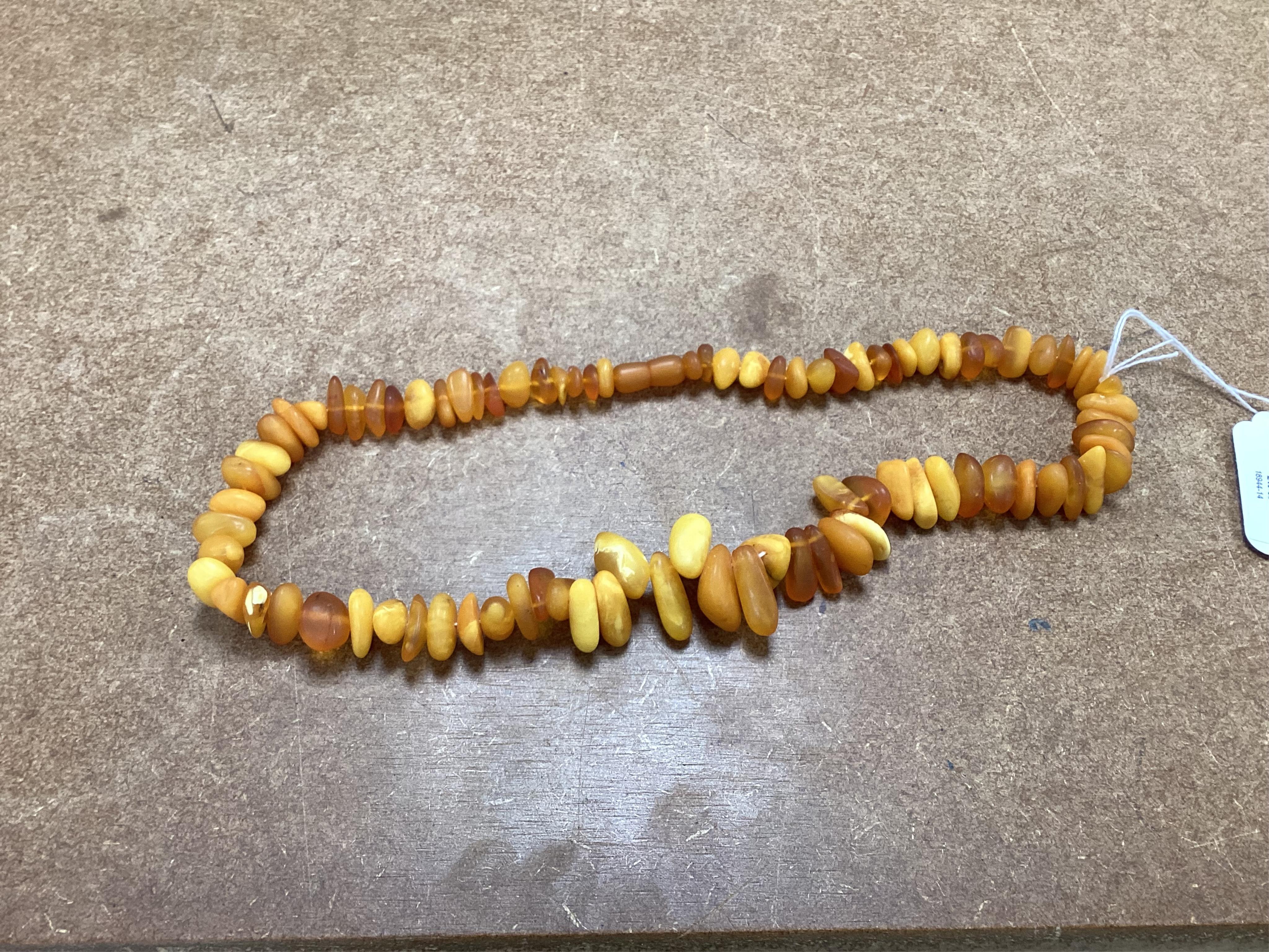 Two necklaces, comprising: a multi-strand coral necklace of torsade design, spaced by beads set with various hardstones, length 73cm; and an amber bead necklace, length 57cm
